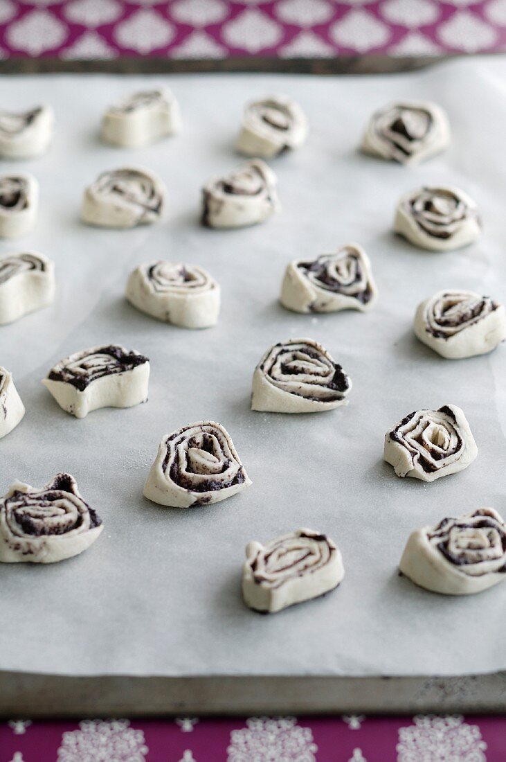Unbaked poppyseed and puff pastry swirls on baking sheet