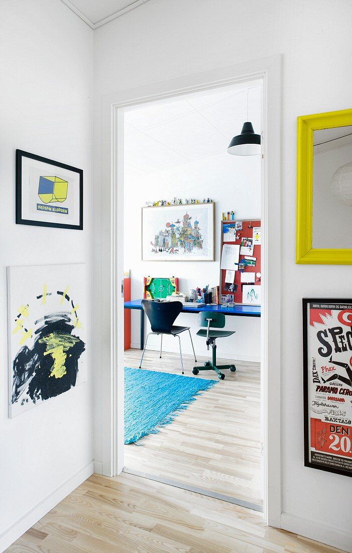 Colourful artworks in hall with view of desk in teenager's bedroom