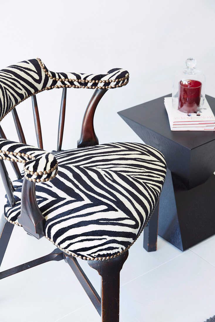 Upholstered chair with zebra pattern cover next to a modern side table