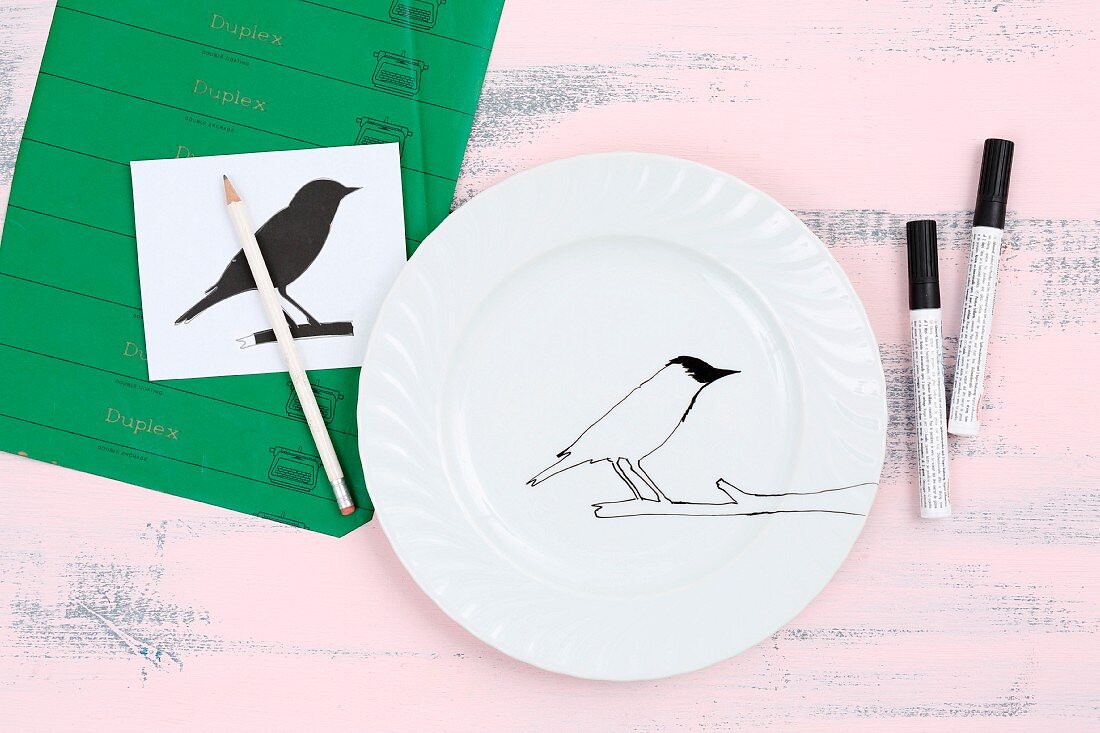 Weißer Teller wird mit einer Vogelsilhouette bemalt