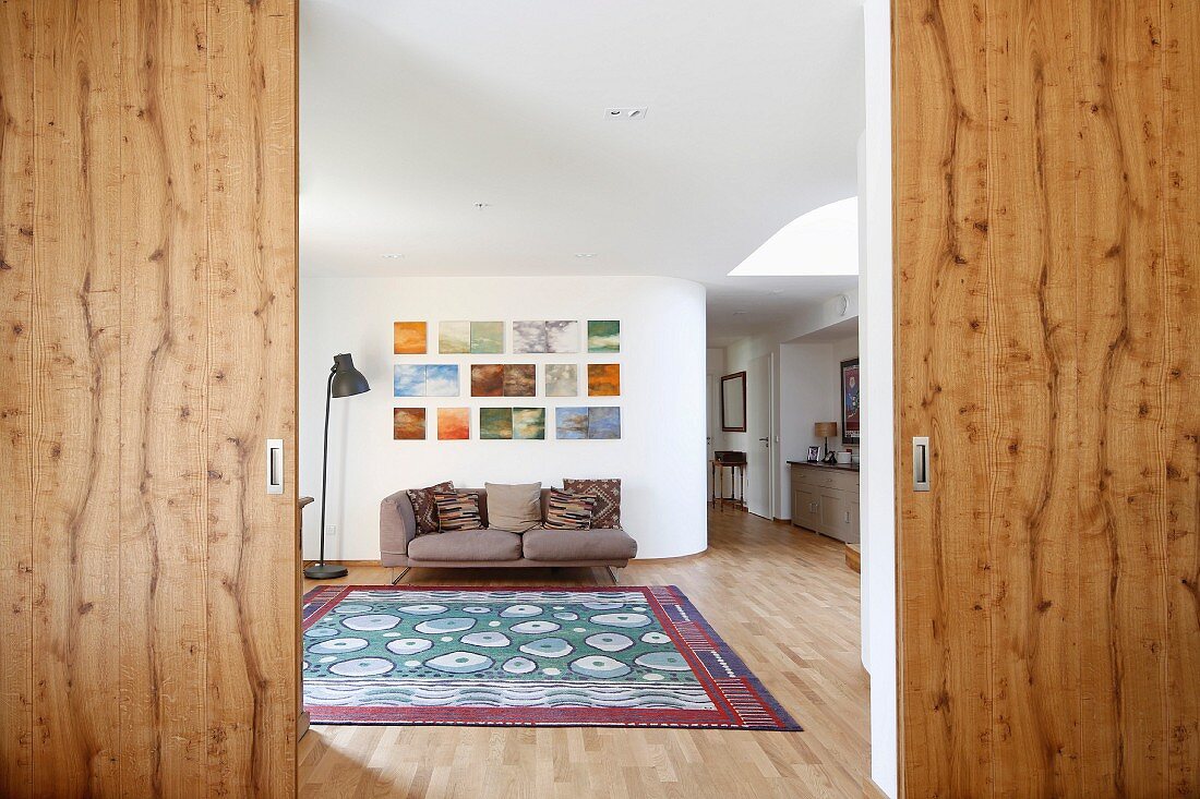 Geöffnete Holzschiebetüren, Blick in eleganten Wohnbereich mit Bildergalerie
