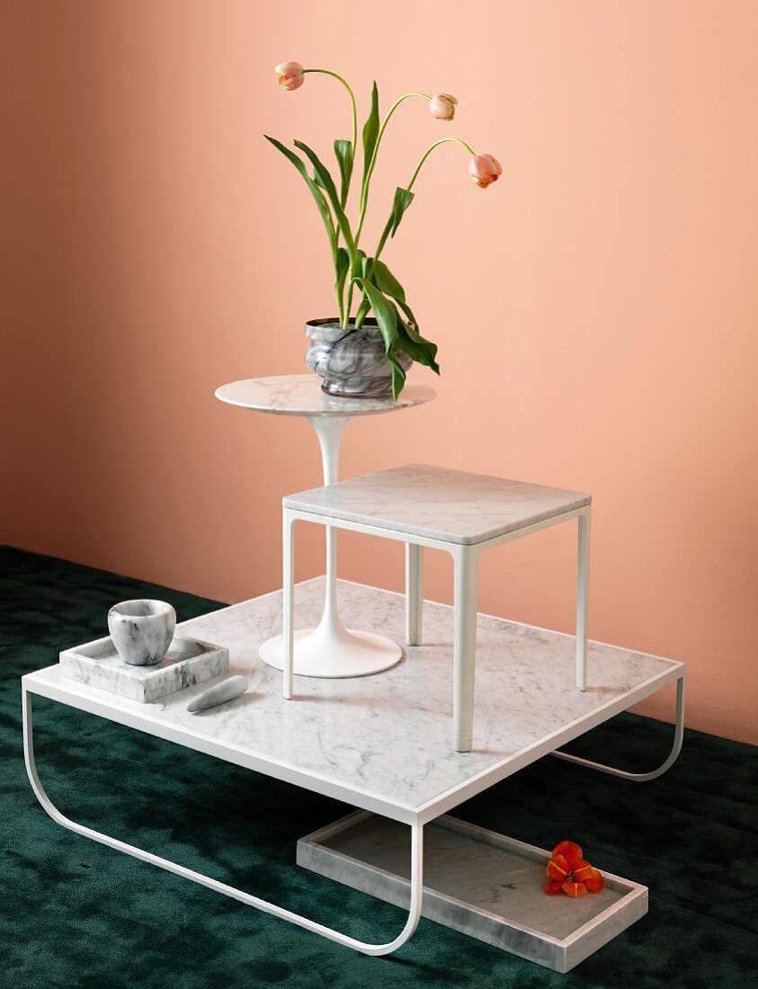 Arrangement mit verschiedenen Tischen und Gegenständen aus weißem Marmor mit Tulpendekoration