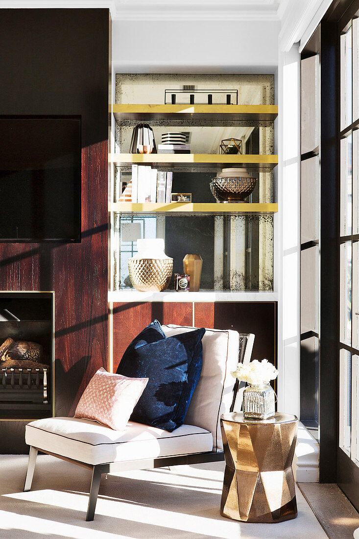 Sessel und goldener Beistelltisch vor eleganter Wohnzimmerwand
