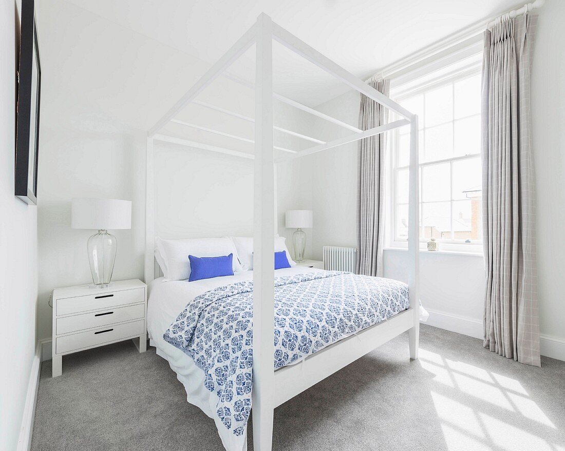 Schlafzimmer mit weißem Himmelbett und grauem Teppichboden