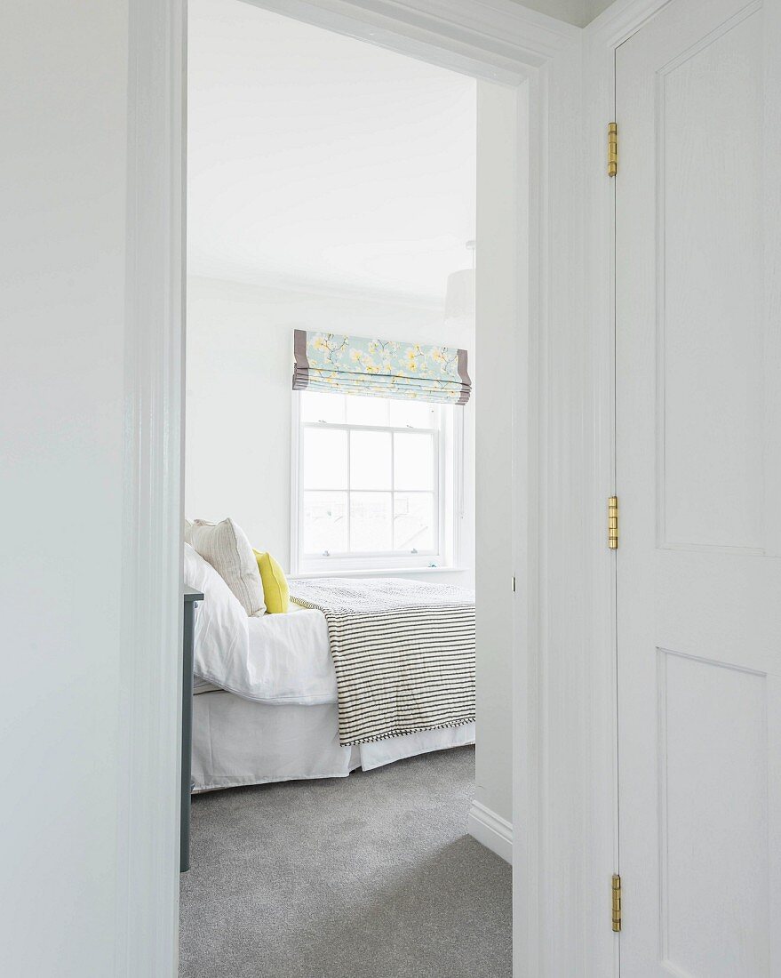 A view of a bright guest room with a lattice window and a grey carpet in an old building