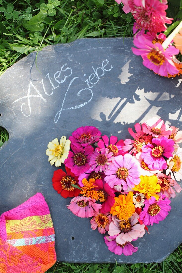 Herzförmiges Blumengesteck auf Schiefertafel mit Botschaft