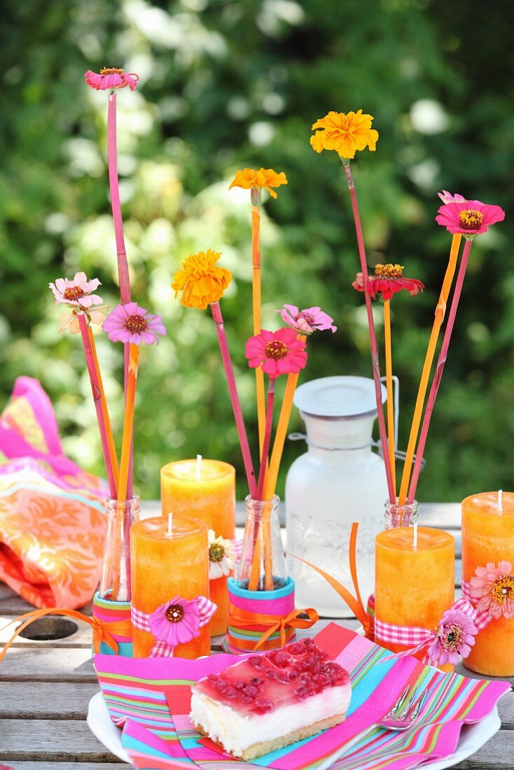 Bunte Tischdekoration mit Blumen und orangefarbenen Kerzen