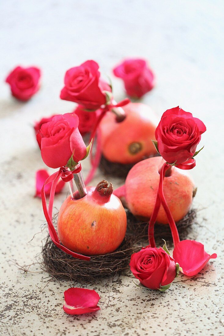 Romantische Tischdekoration mit Rosenblüten und Granatäpfeln