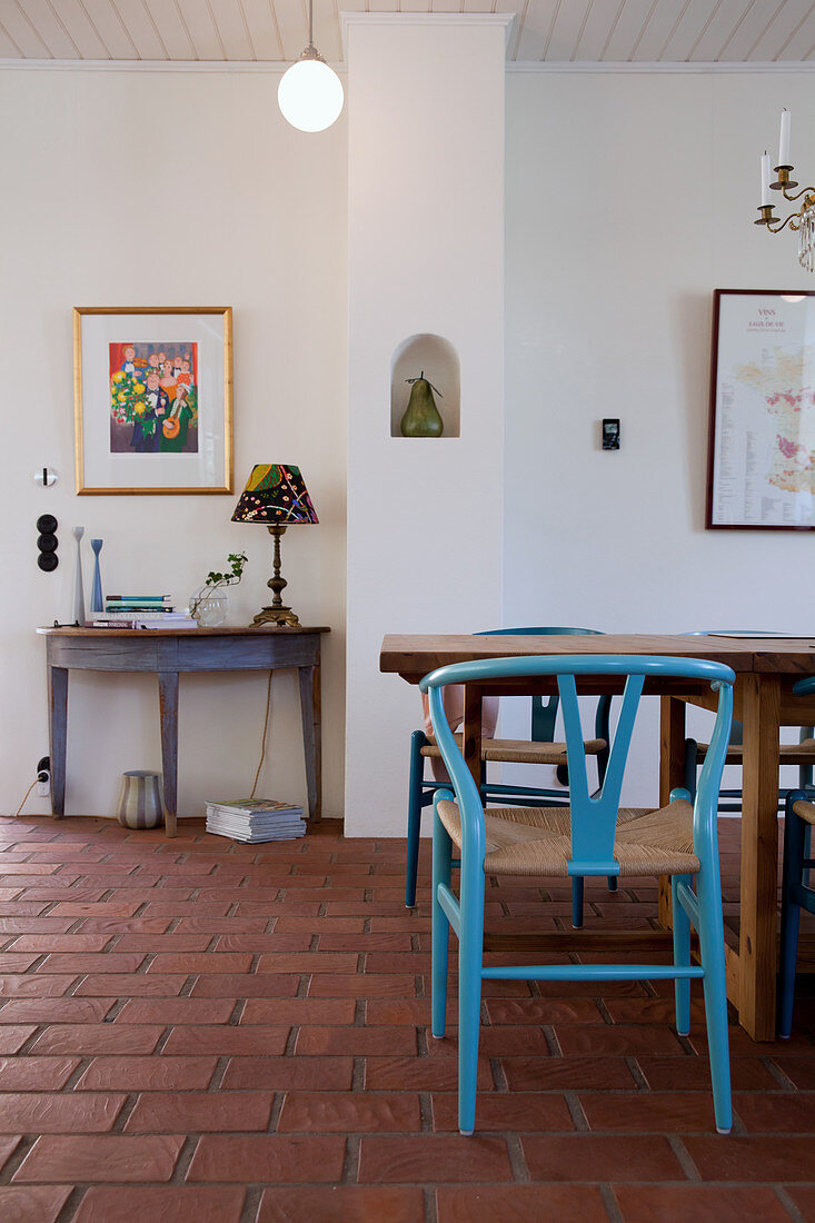 Blauer Designerstuhl am Esstisch auf Terracottafliesenboden