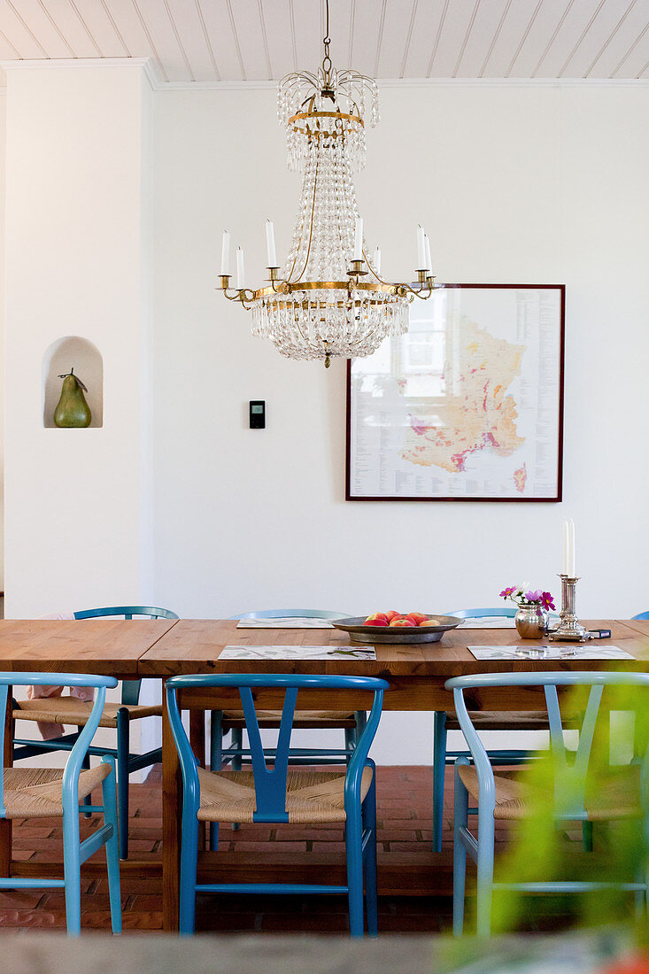 Chandelier above dining table and blue designer chairs