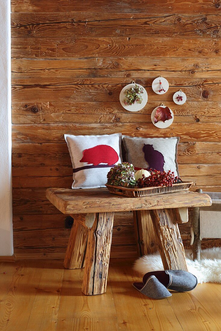 Kleine Bilder aus Filzresten an Holzwand und Kissenhülle mit Filzmotiv in Hüttenambinete