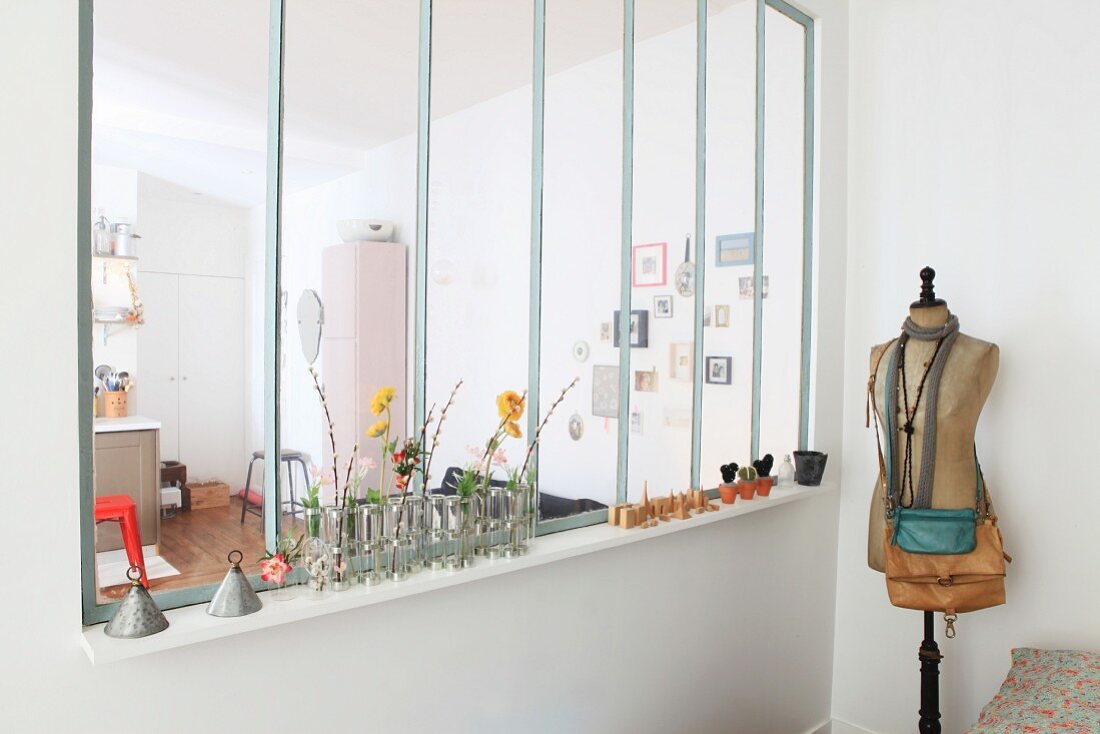 Handbags on vintage tailors' dummy and small vases of flowers on interior windowsill