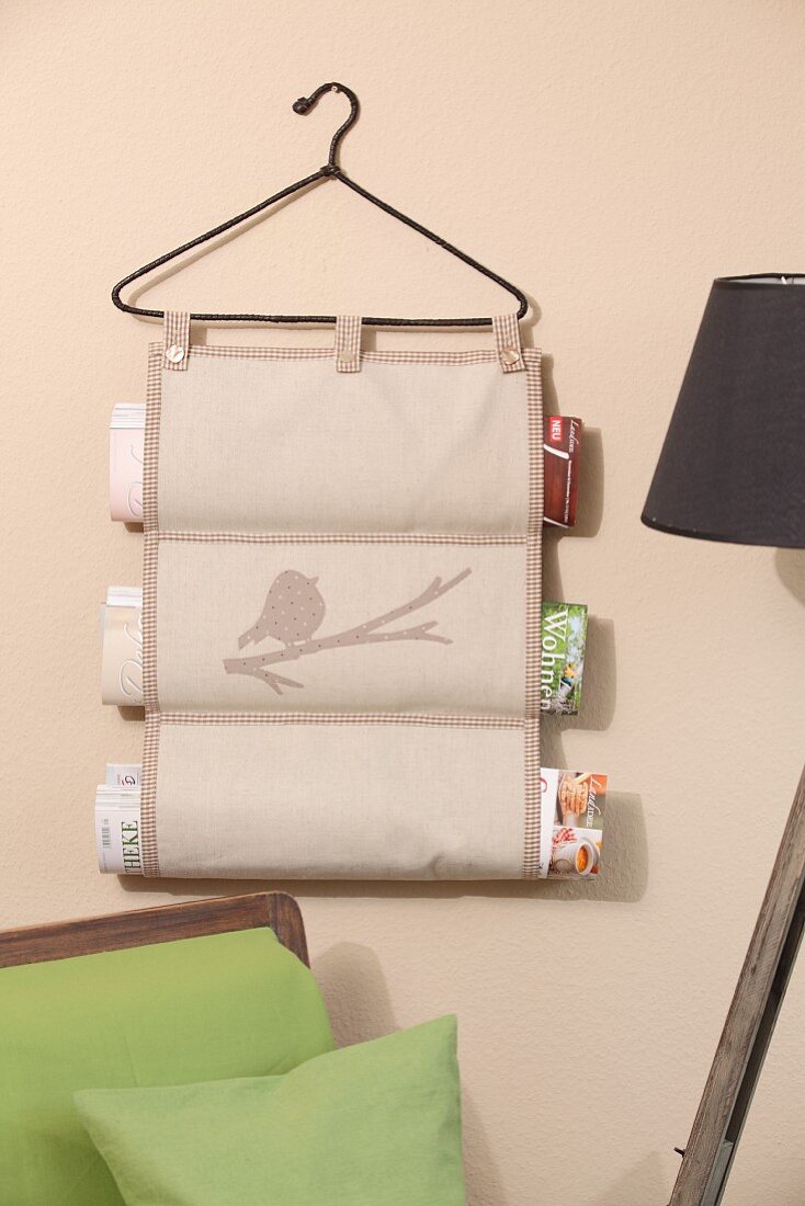 Hand-sewn magazine rack hanging from vintage coat hanger on wall