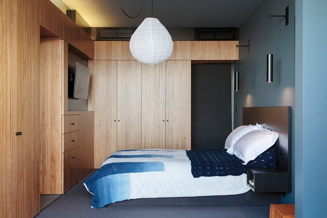 Schlafzimmer mit Einbaumöbeln und Bett vor blauer Wand