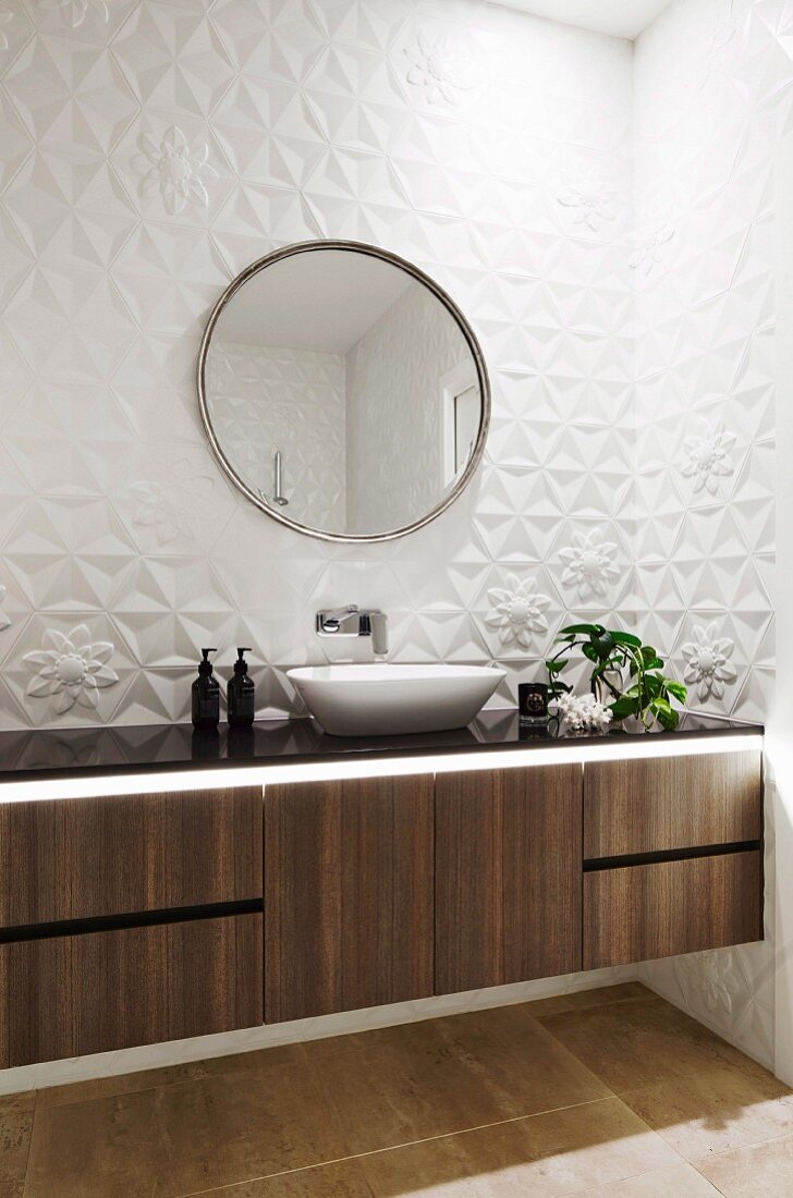 Badezimmer mit Waschtischmöbel und weissen, dreidimensionalen Wandfliesen