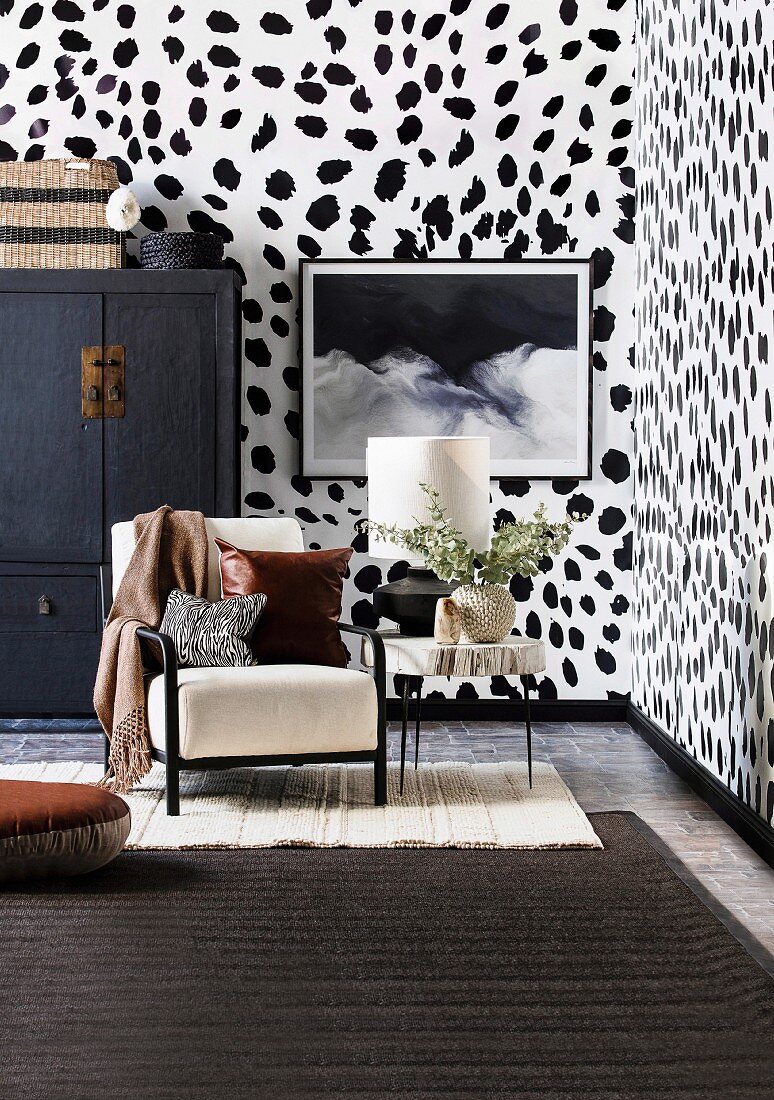 Upholstered chair, side table and Chinese cupboard in the living room with Dalmatian wallpaper