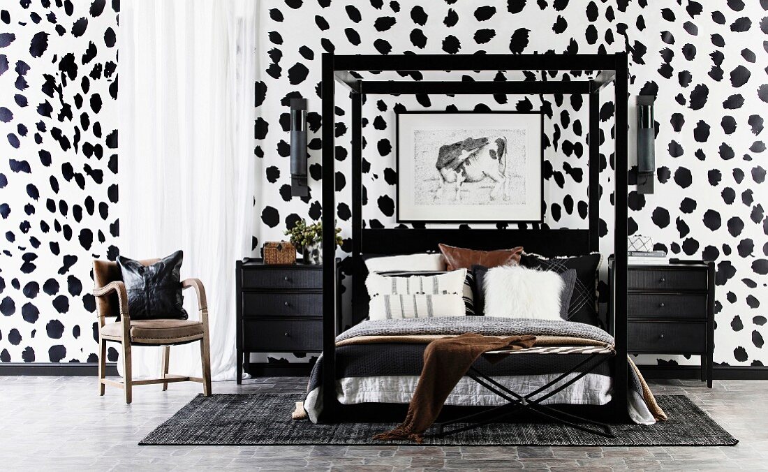 Doppelbett mit schwarzem Rahmen und schwarze Nachtkästechen vor Wand mit Dalmatiner-Tapete