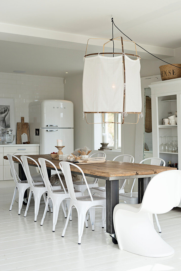 Langer Esstisch mit weißen Stühlen in der offenen Küche