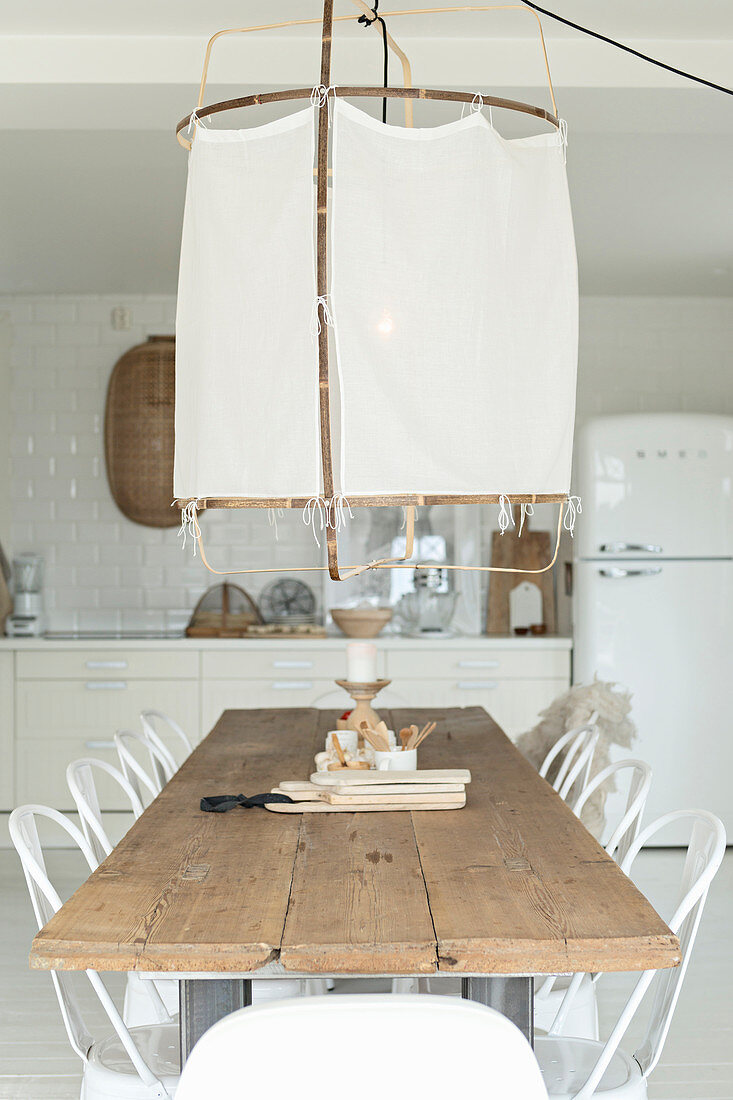Large ceiling lamp above long dining table in open-plan kitchen