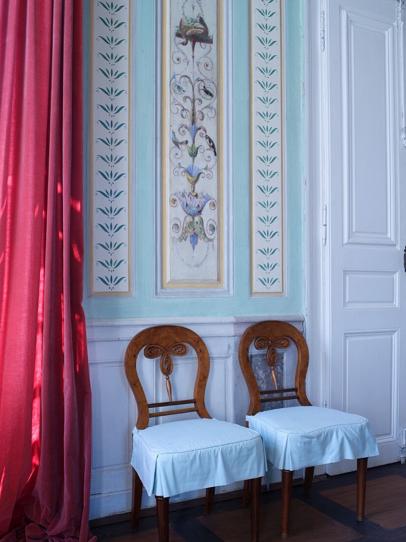 Two chairs against painted panelled wall