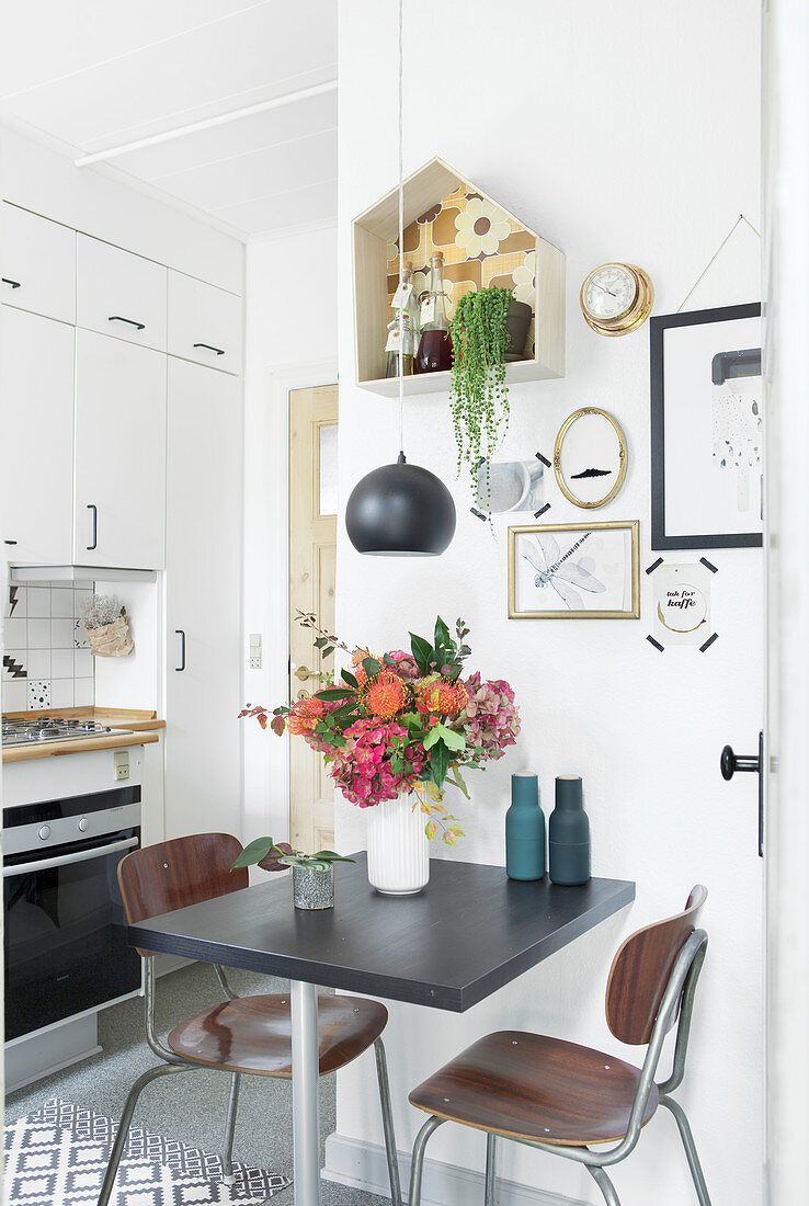 Kleiner Essplatz in der Küche mit Blumenstrauß und dekorierter Wand