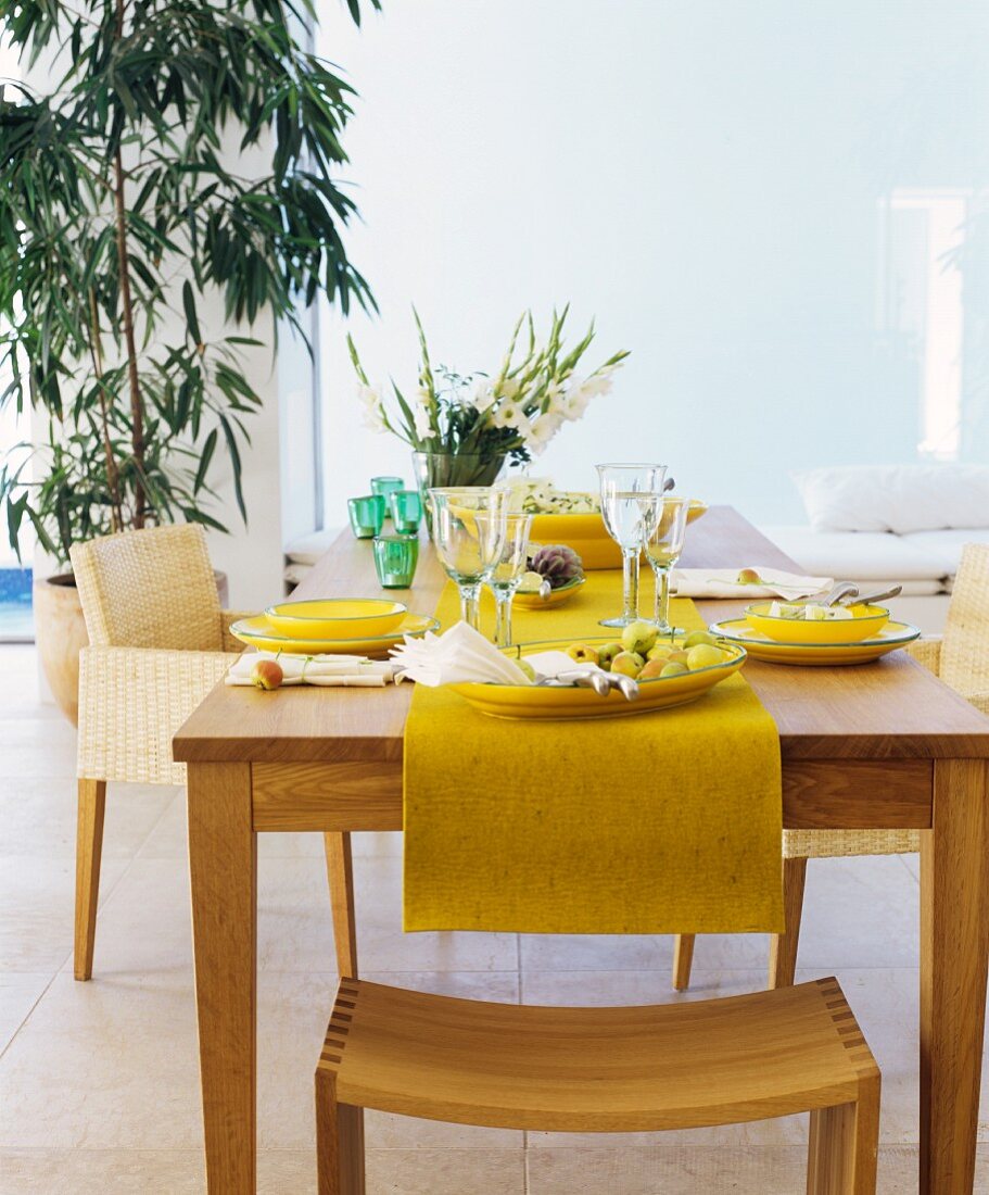 Holztisch mit Tischläufer aus Filz und gelbem Geschirr