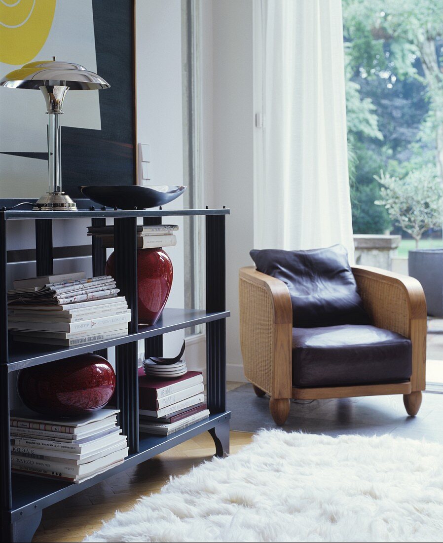 Armchair with leather seat cushion next to open black shelving and white flokati rug