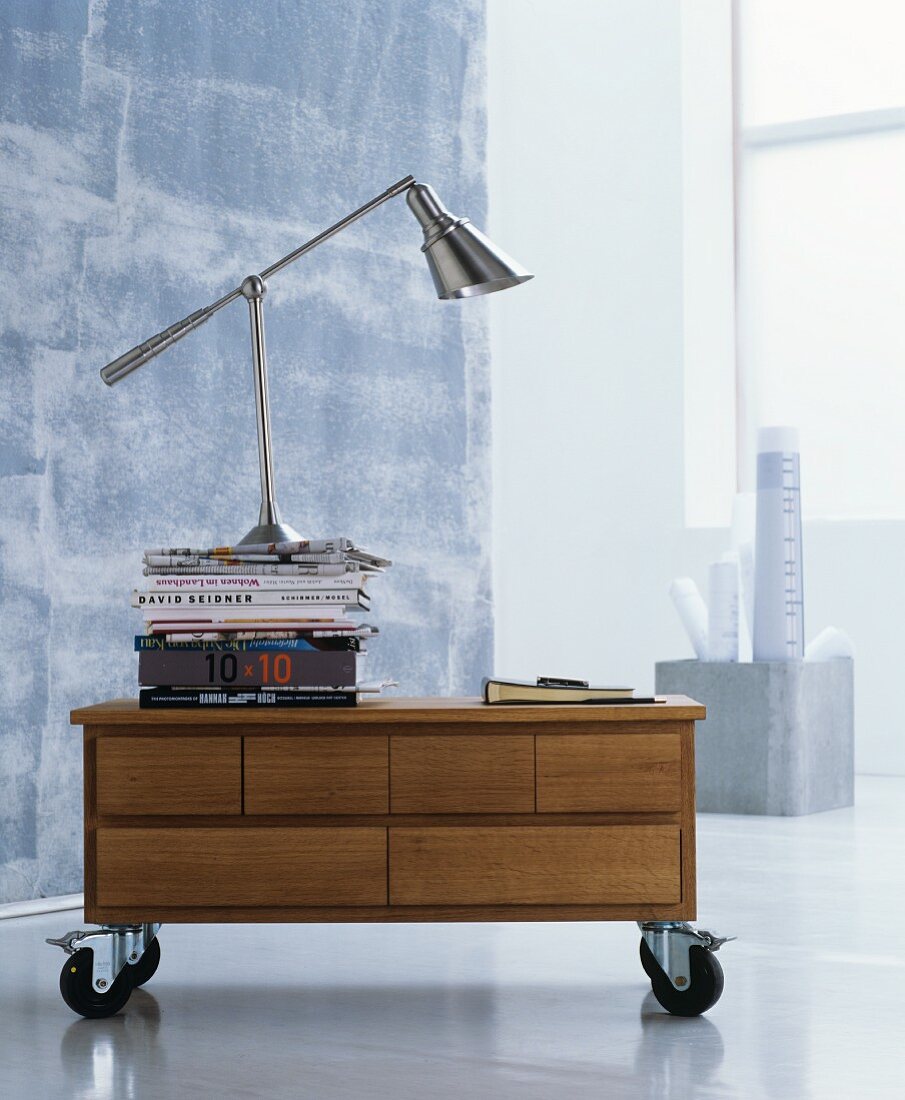 Stacked books and designer lamp on top of low sideboard on castors