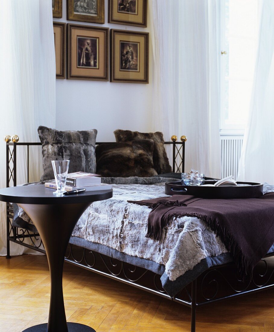 Fur cushions and fur blanket on black bed next to black table