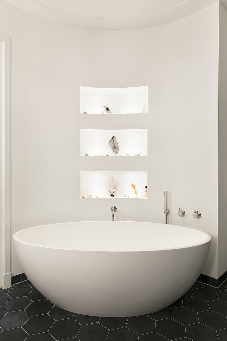 Ovale freistehende Badewanne vor halbrunder Wand mit Nischen