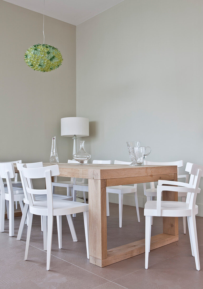 weiße Stühle um einen modernen Holztisch im schlichten Esszimmer
