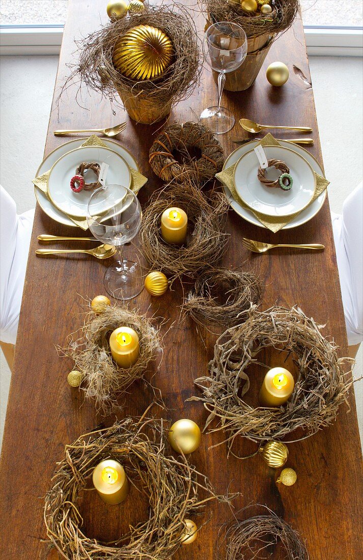 Mehrere rustikale Kränze und goldfarbene Kerzen als weihnachtliche Tischdekoration
