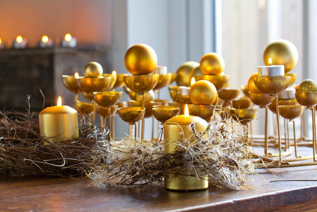 Goldfarbene Kerzenständer mit Kerzen und Kugeln und rustikale, getrocknete Kränze