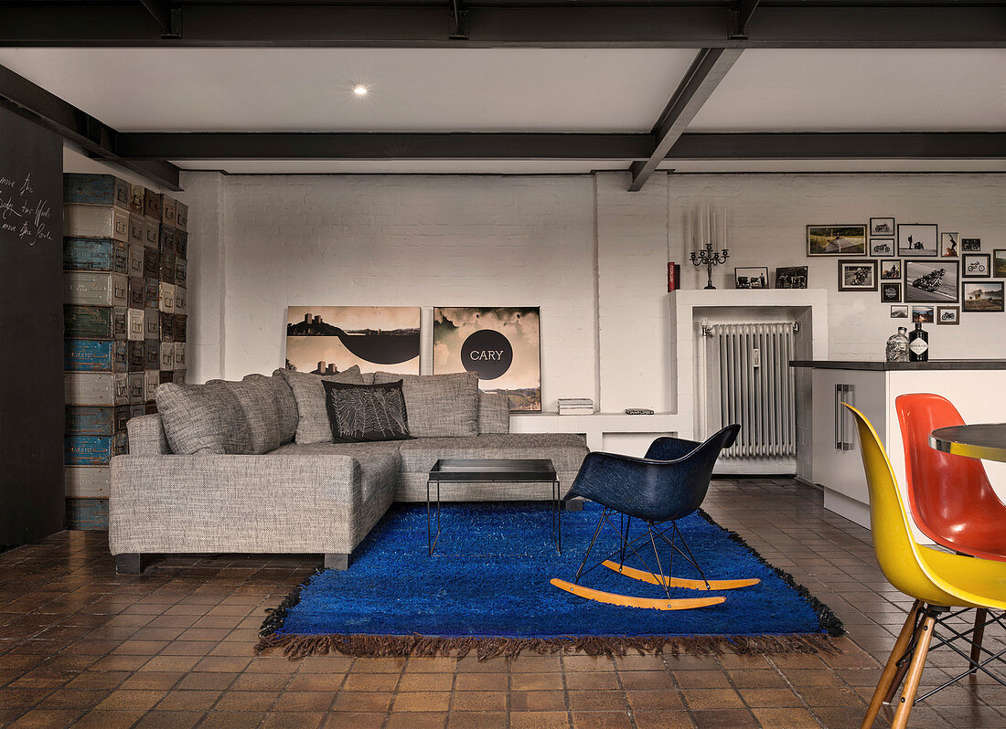 Grey sofa on blue rug in open-plan industrial-style interior
