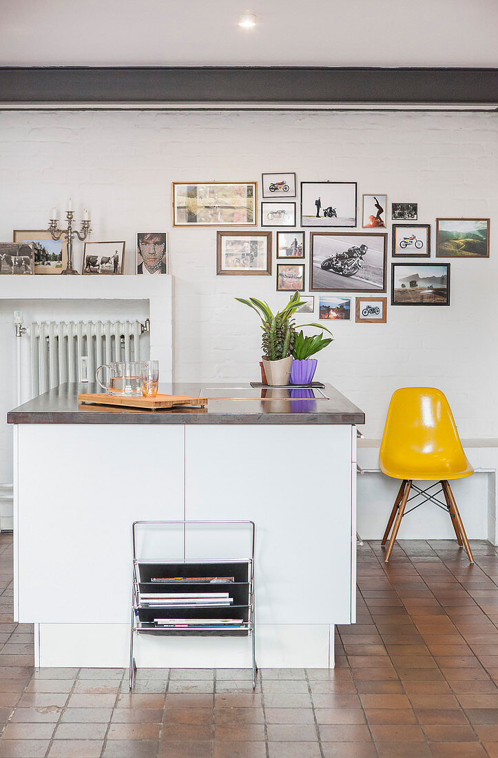 Kücheninsel und ein Designerstuhl vor einer Wand mit Bildergalerie