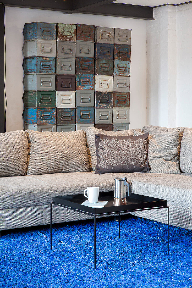 Black coffee table and grey sofa on blue rug