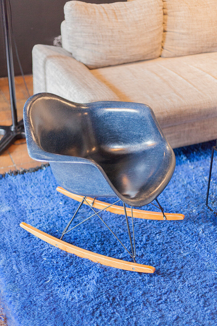 Blauer Designer-Schaukelstuhl auf knallblauem Teppich