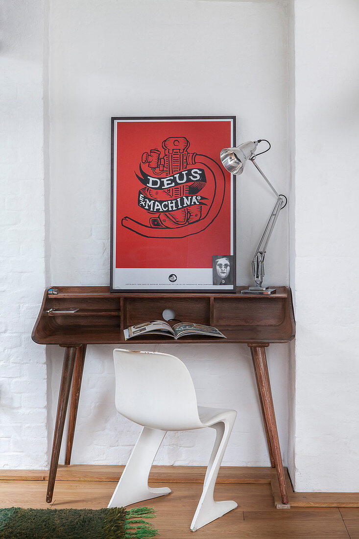 Weißer Designerstuhl vor einem Schreibtisch aus Holz mit rotem Bild