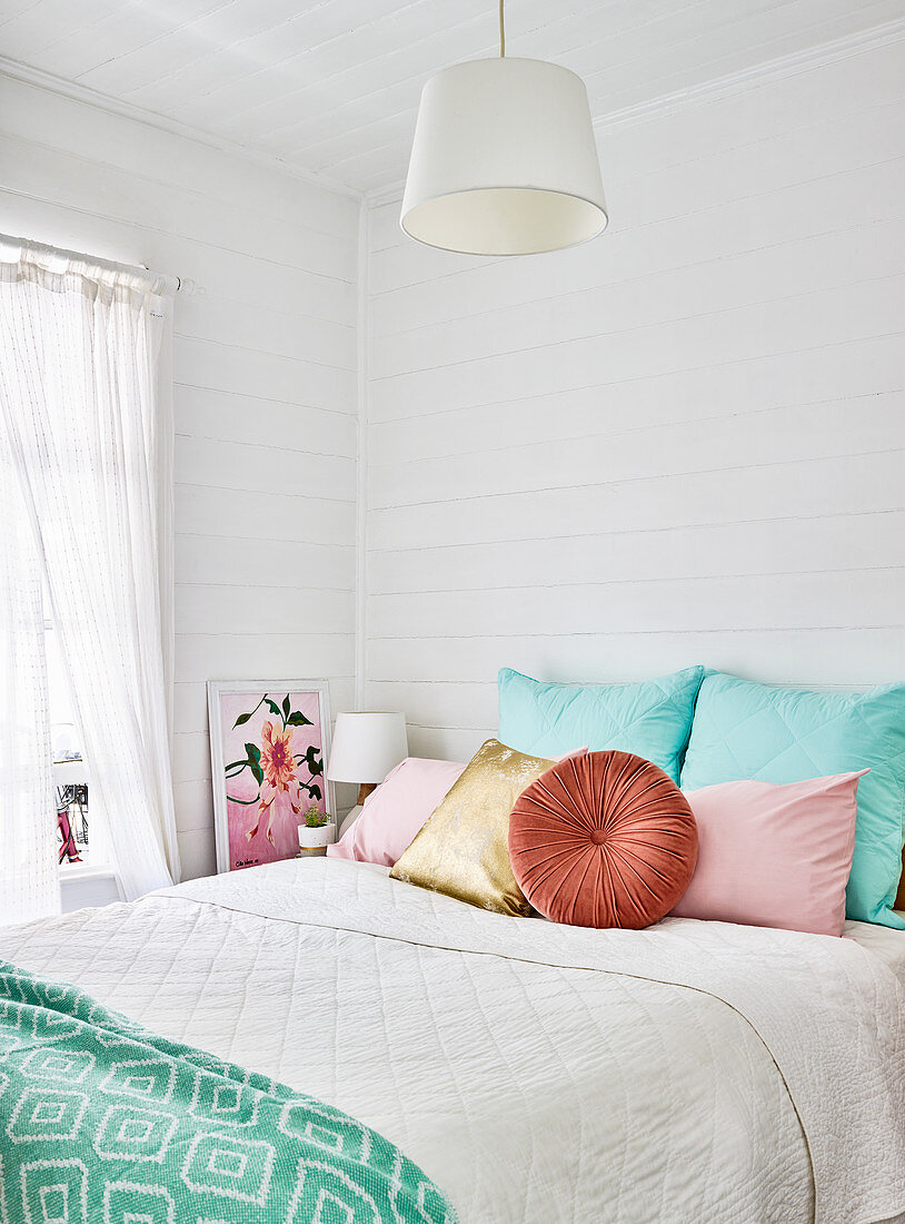 Bunte Kissen auf dem Bett im Schlafzimmer mit Bretterwand