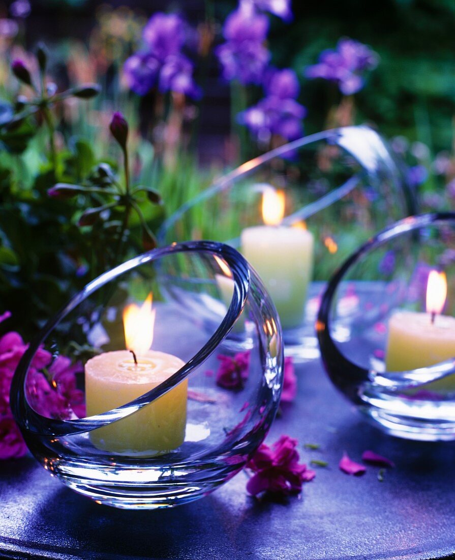 Brennende Kerzen in Glasschalen mit schräger Öffnung als stimmungsvolle Tischdekoration