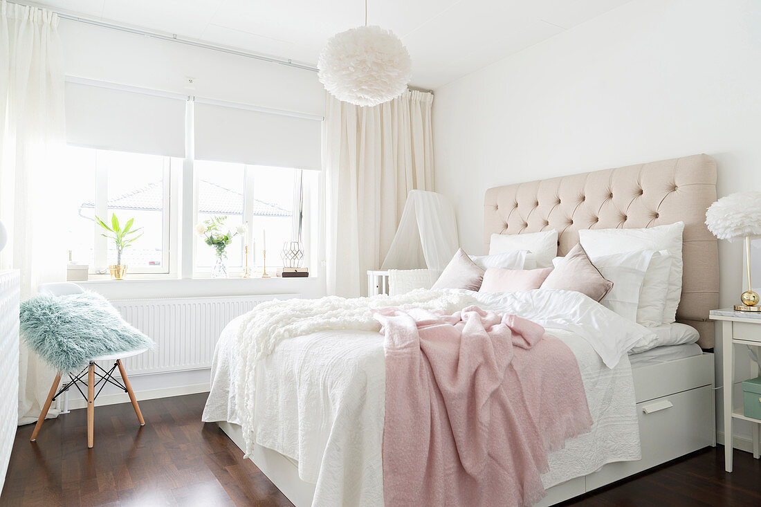 Doppelbett mit Betthaupt im Schlafzimmer in weißen und hellen Pastelltönen