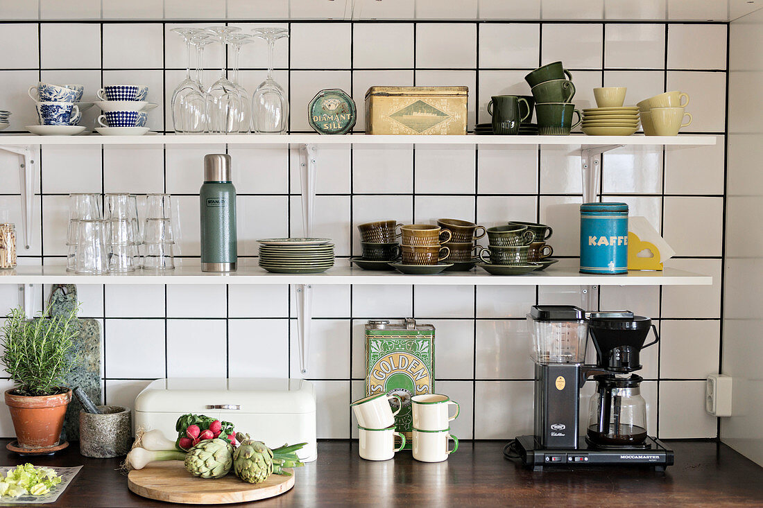 Green cups and old tins on kitchen shelves above worksurface