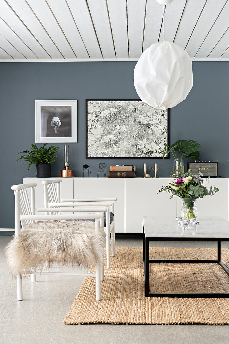 weiße Stühle vor dem Couchtisch im Wohnzimmer mit grauen Wänden