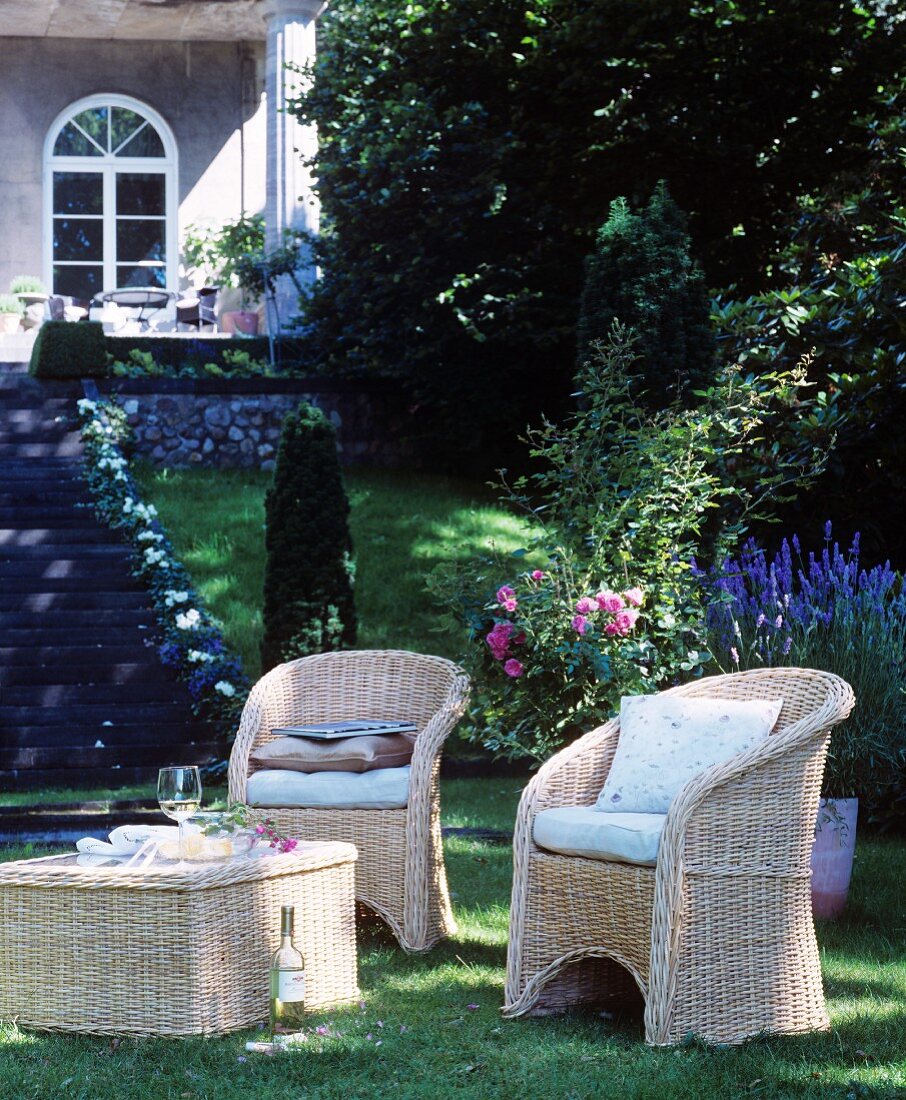 Schattiger Sitzplatz mit Korbmöbeln im klassischen Sommergarten