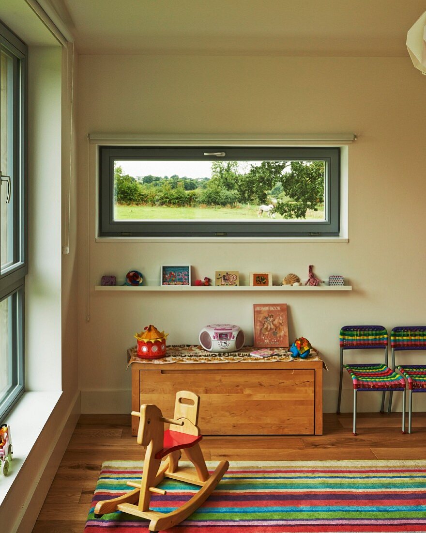 Schaukelpferd im Kinderzimmer mit horizontalem Fenster