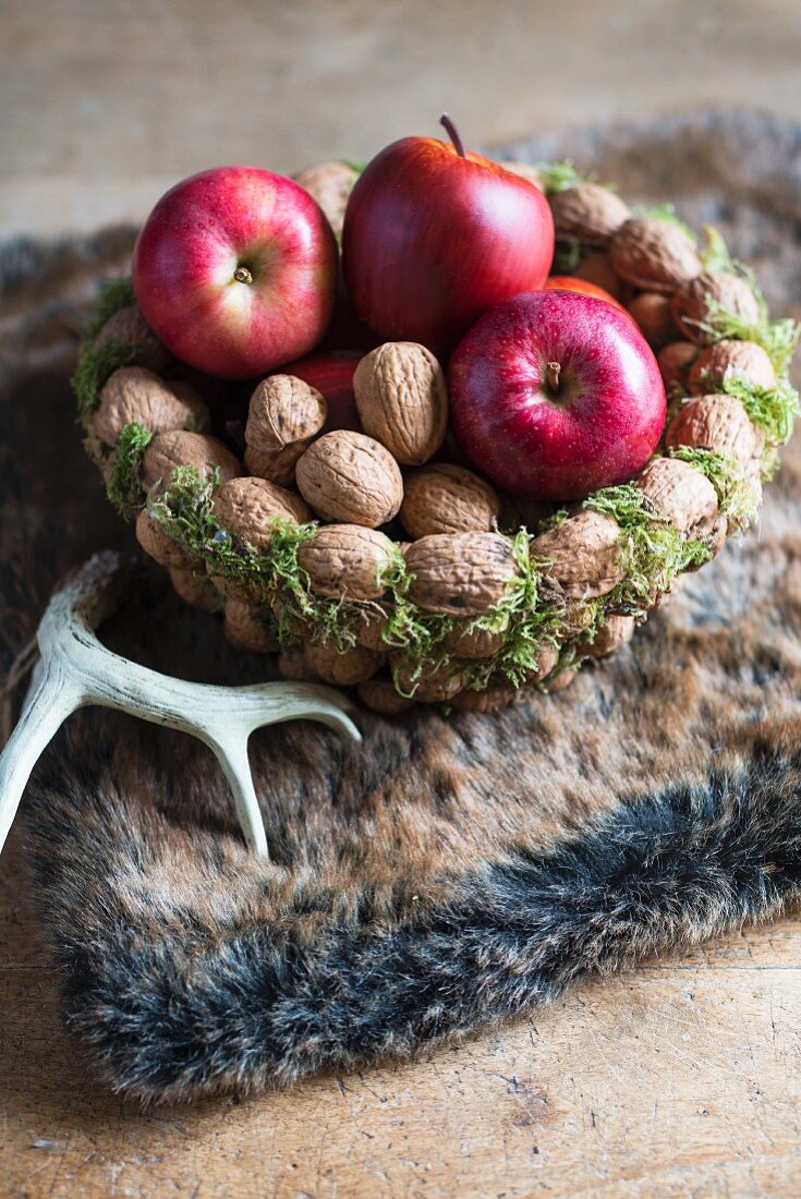 Walnüsse und Äpfel in einem Korb aus Walnüssen (Weihnachtsdeko)
