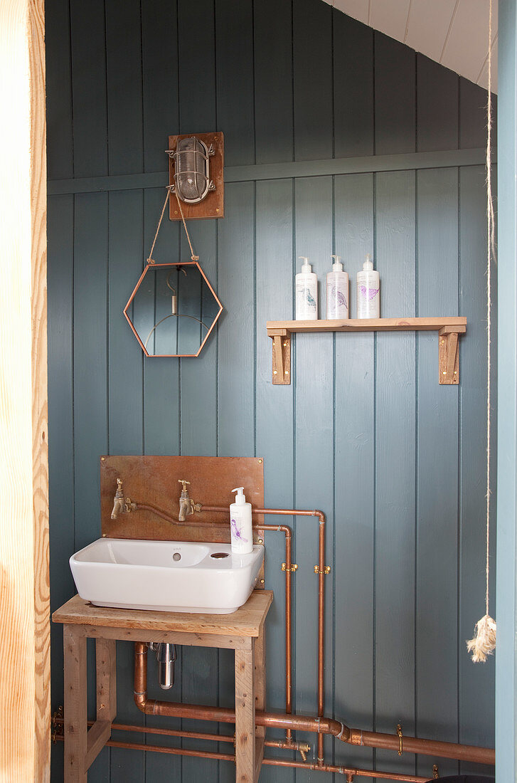 Rustic bathroom with copper pipes on blue board wall
