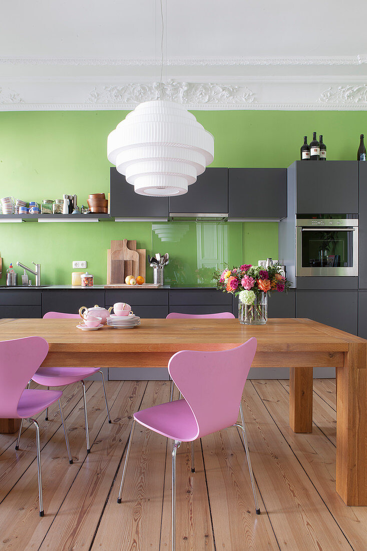 Esstisch in der grauen Küche mit grüner Wand und Stuckdecke