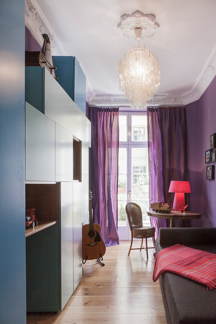 Blaue Schrankmodule im kleinen Gästezimmer mit violetter Wand