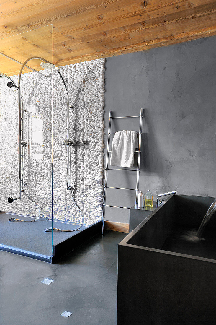 Duschwand mit weißen Kieselsteinen im grauen, modernen Bad
